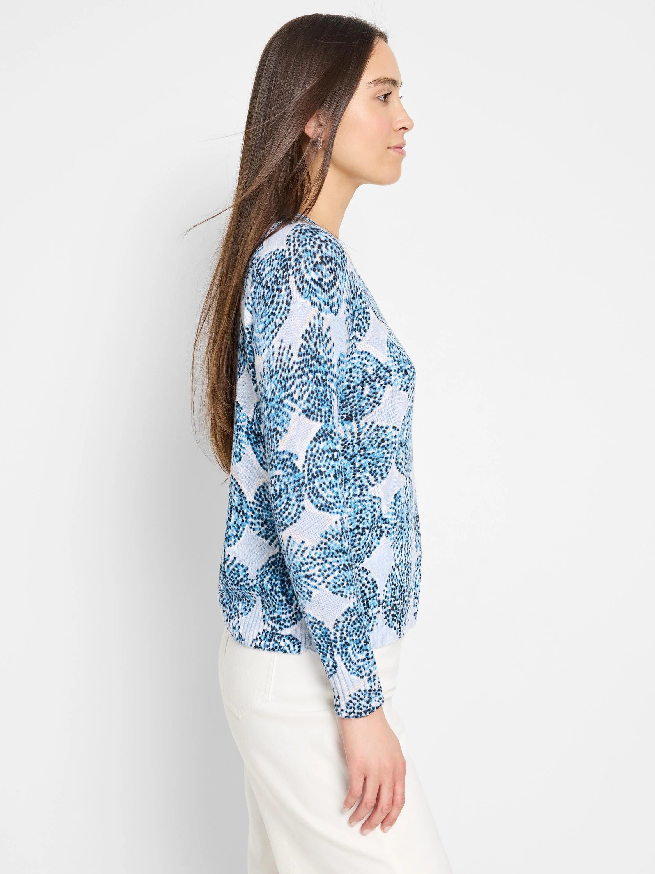 Light blue sweater with a darker blue, speckled floral pattern.  Long sleeves, ribbed cuffs.
