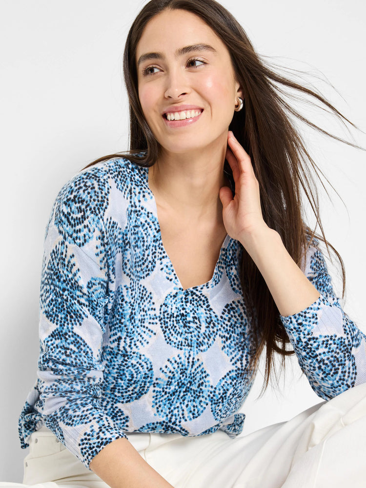 Light blue sweater with a v-neck and a blue and white circular pattern.  Three-quarter sleeves.