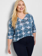 Light blue sweater with a V-neck and dark blue, speckled circular pattern. Three-quarter sleeves.