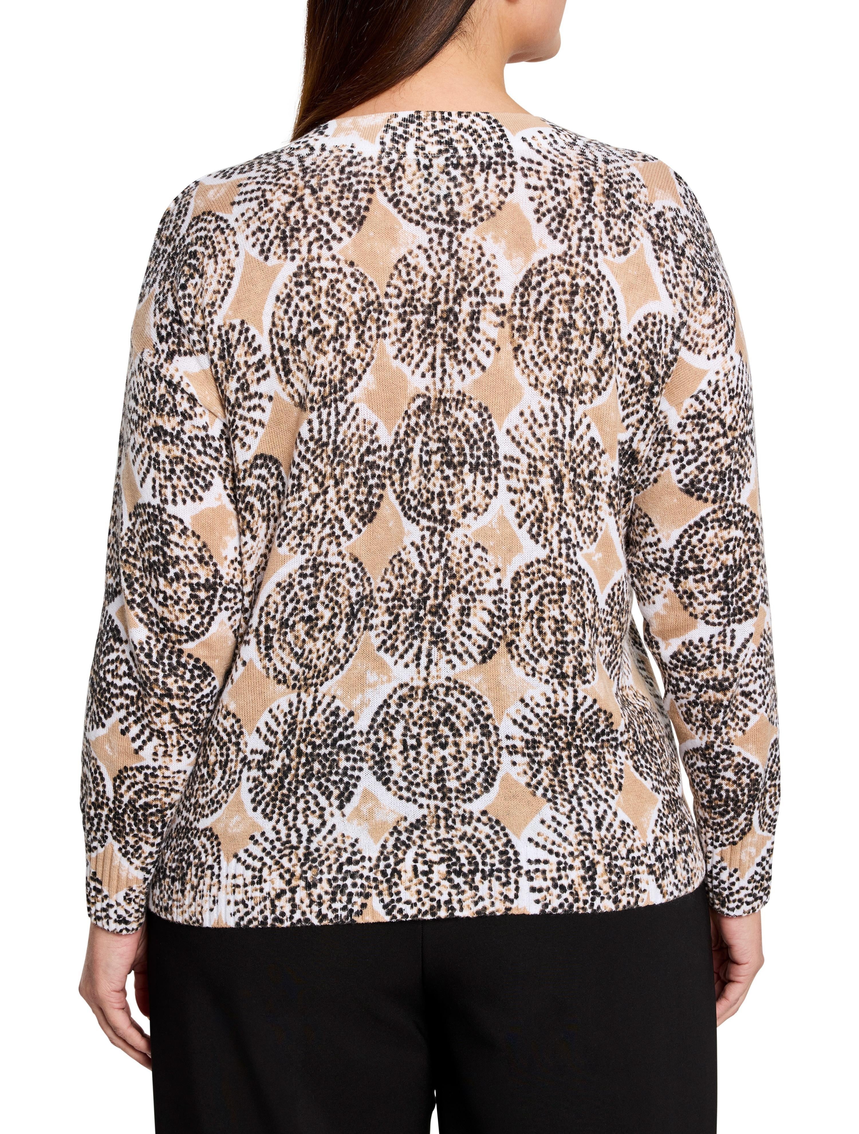 Beige sweater with a pattern of dark brown and black small dots forming circular shapes on a white and beige background....