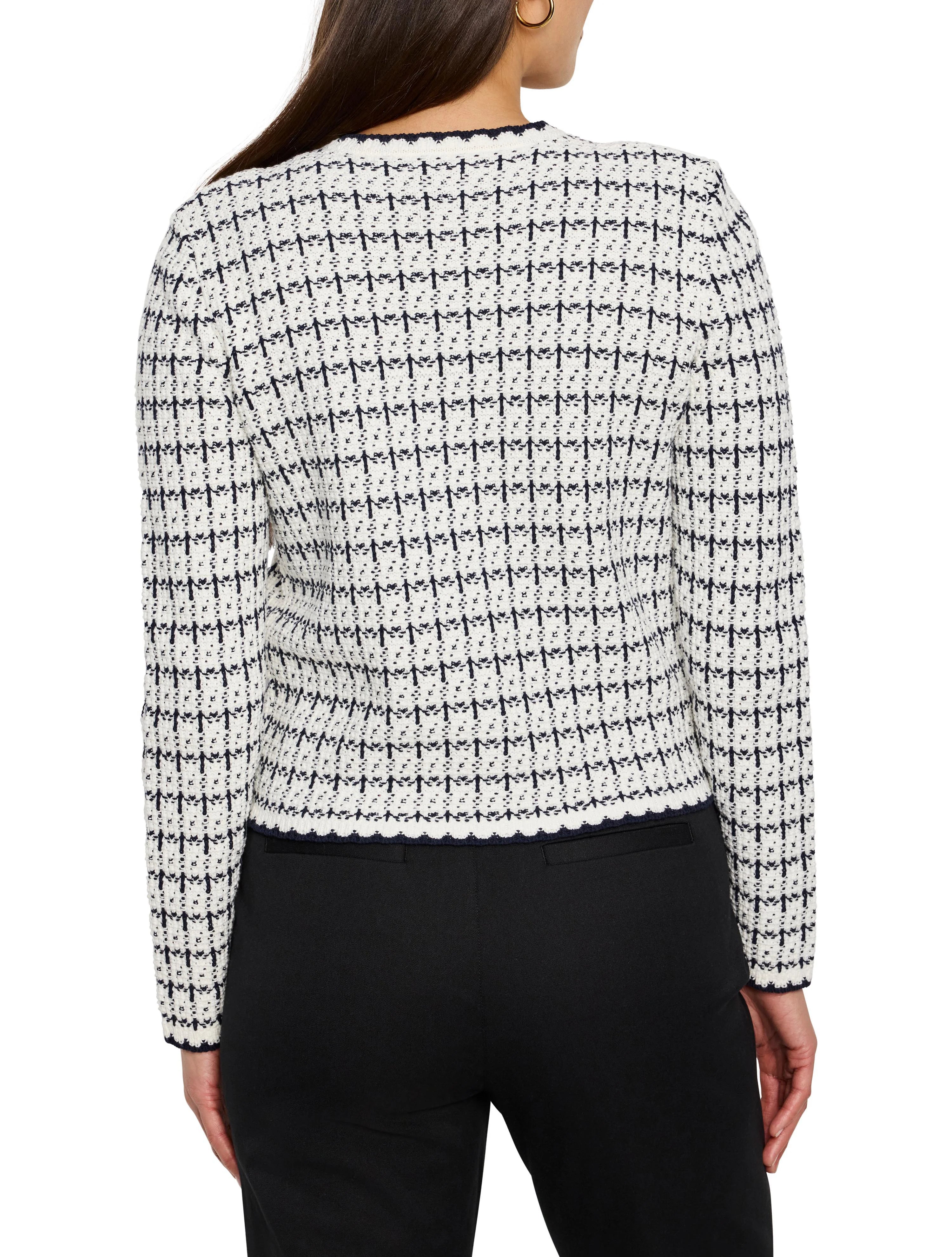 Back view of a white & navy knit sweater jacket with a small, textured grid pattern & scalloped navy trim.