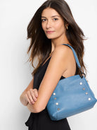 Dusty blue leather handbag with silver studs and a shoulder strap.