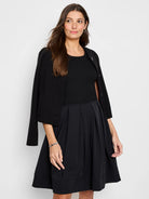 Black A-line dress with pleated skirt and fitted bodice.  Model also wears a black cardigan.
