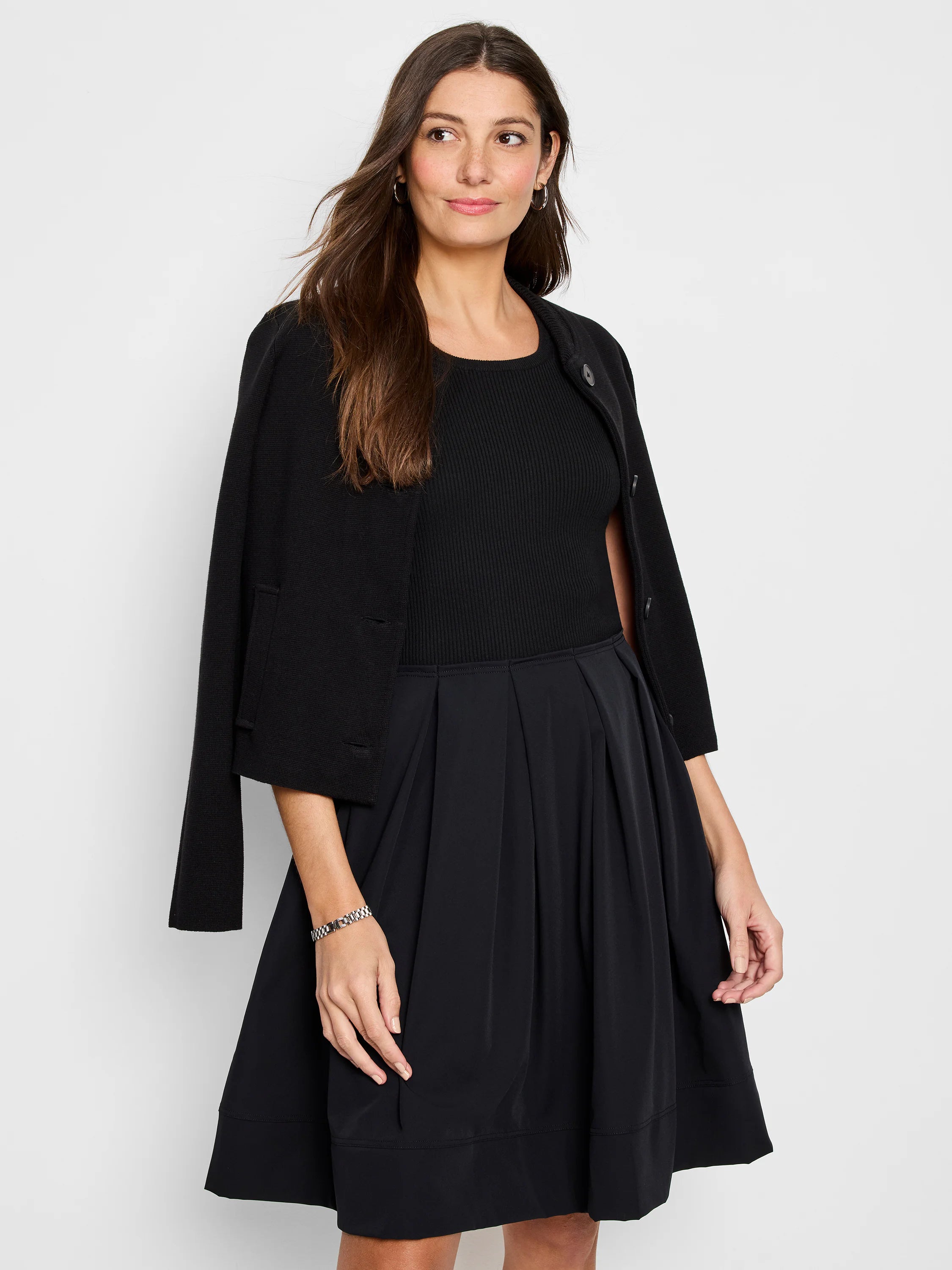 Black A-line dress with pleated skirt and fitted bodice.  Model also wears a black cardigan.