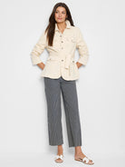 Wide-leg jeans with thin, dark-blue stripes on an off-white background.  Model wears cream-colored jacket.