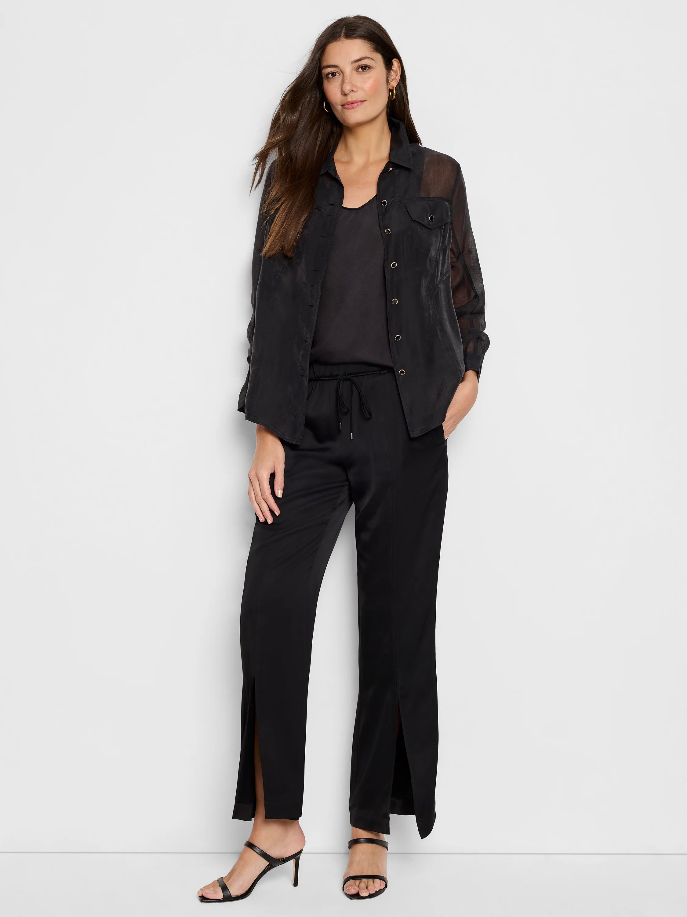 Black sheer jacket with gold buttons, worn over black top and trousers with side slits.