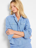 Light blue textured shirt jacket with silver buttons and flap pockets. Long sleeves.