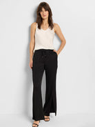 Black wide-leg pants with side slits, drawstring waist.  Model wears off-white camisole.