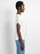 Light cream woven tee with wide neckline and draped short sleeves. Flowy fit.