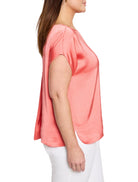 Coral glossy woven tee with wide, short sleeves and a relaxed fit, showing side slits at the hem.