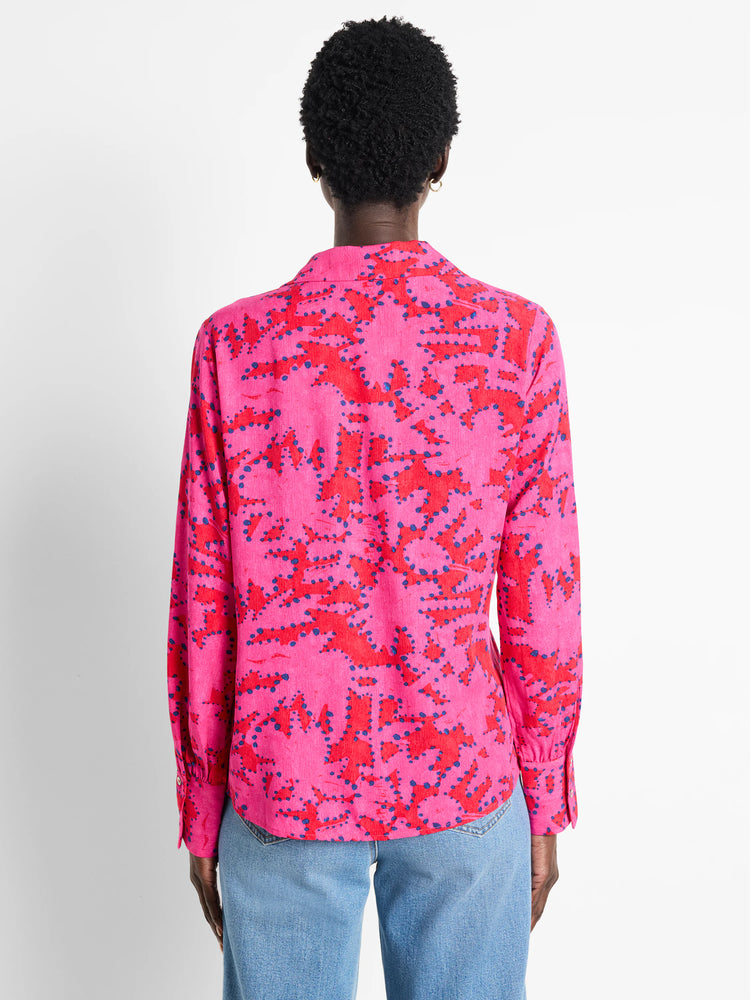 Pink long-sleeve blouse with red and dark blue abstract print.  Buttoned cuffs.