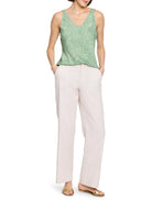 Green sleeveless tank top with a subtle swirling pattern.  V-neck. Model also wears off-white pants and gold sandals.