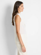 Off-white sleeveless woven tank top;  slightly ruffled neckline.