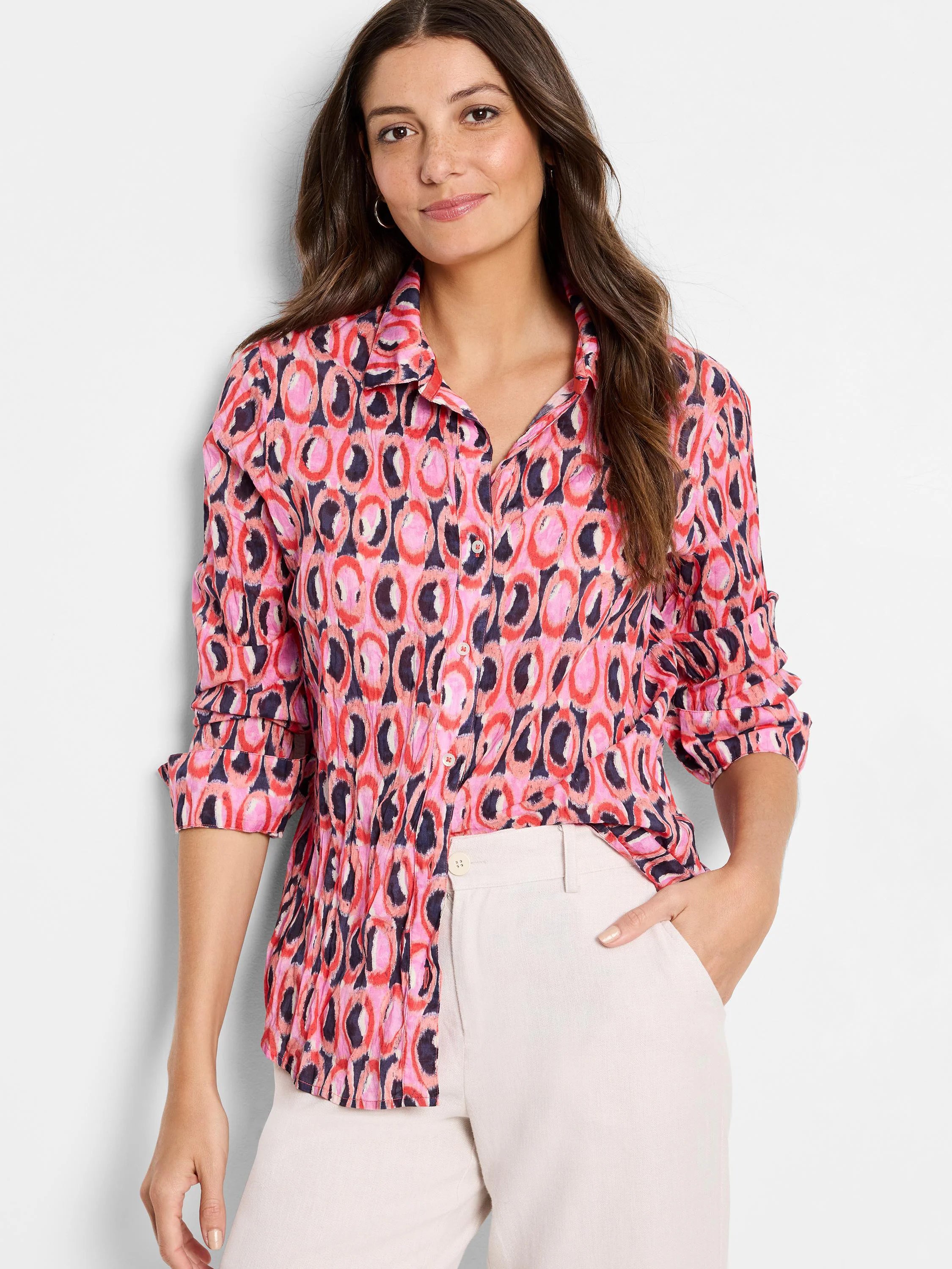Pink cotton shirt with long sleeves.  Ikat-style print features pink, red, and dark blue circular patterns on a lighter...