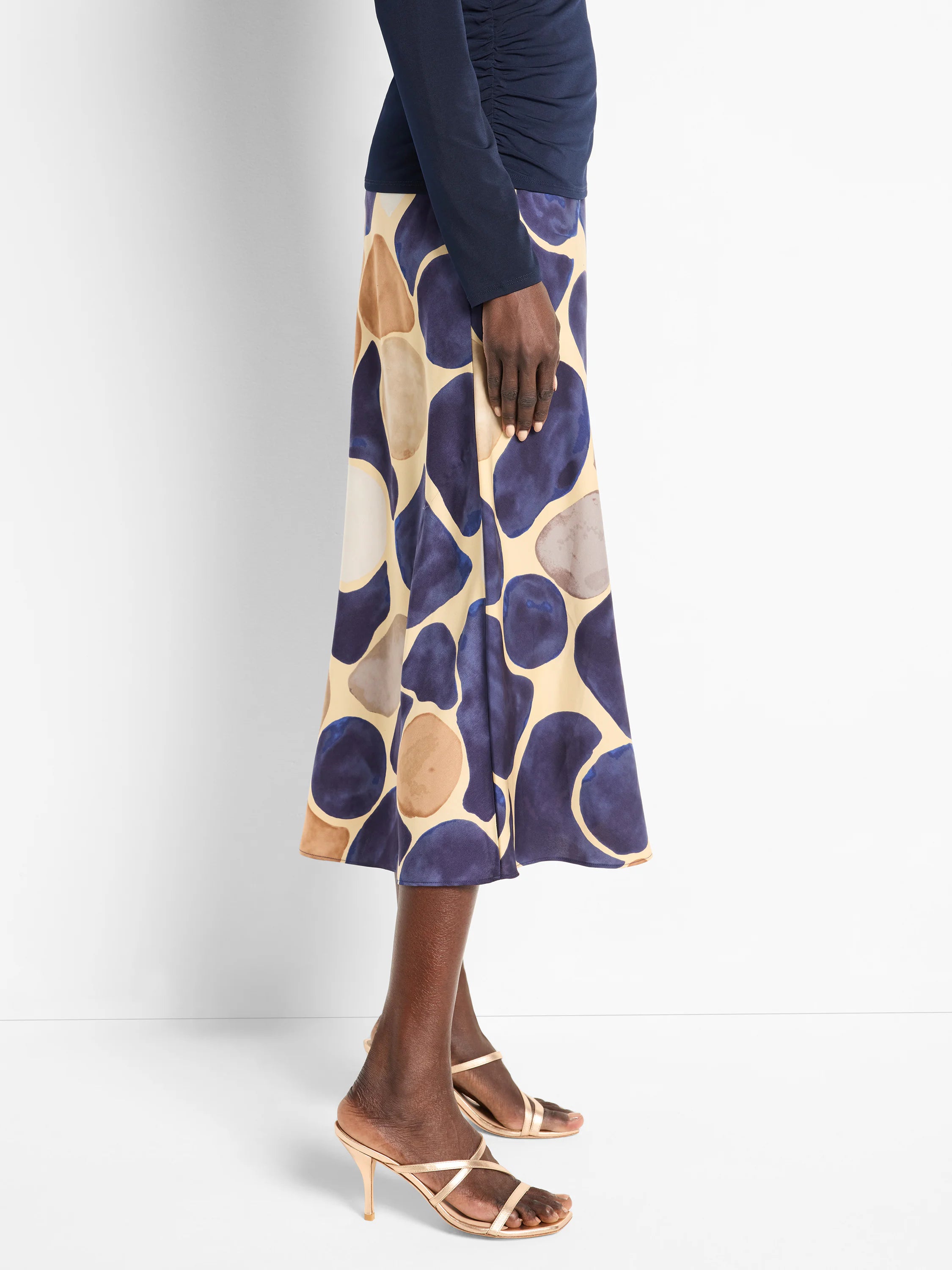 A-line midi skirt in beige with an abstract print of dark blue and brown pebbles.
