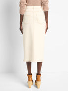 Off-white denim midi skirt with front slit, back pockets, and light brown topstitching.  Rear view.