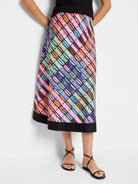 Mid-length A-line skirt, black background with diagonal rainbow stripes of pink, orange, teal, brown & blue, accented...