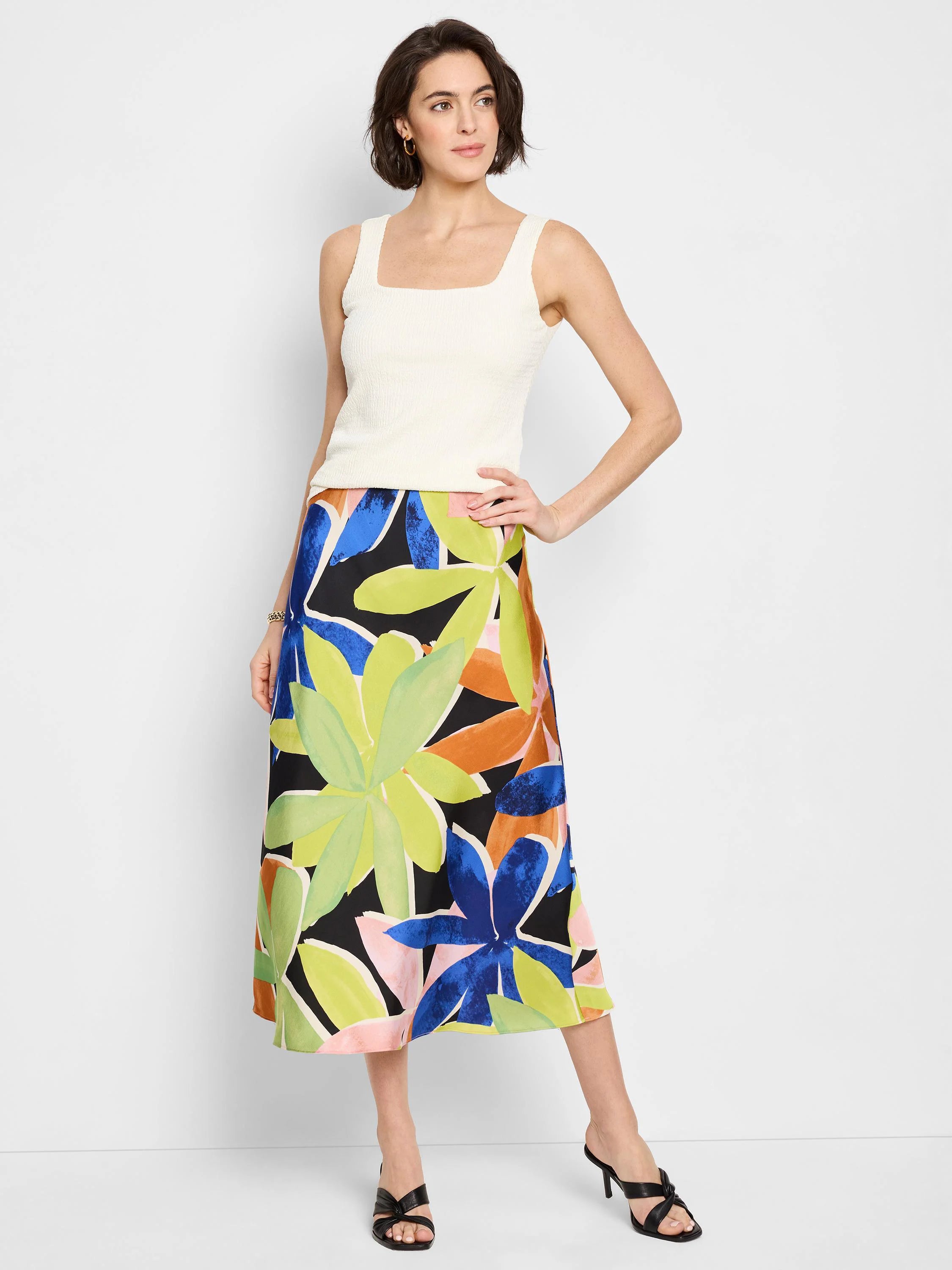 Midi slip skirt with large abstract floral print in lime green, blue, orange, and pink on black background.
