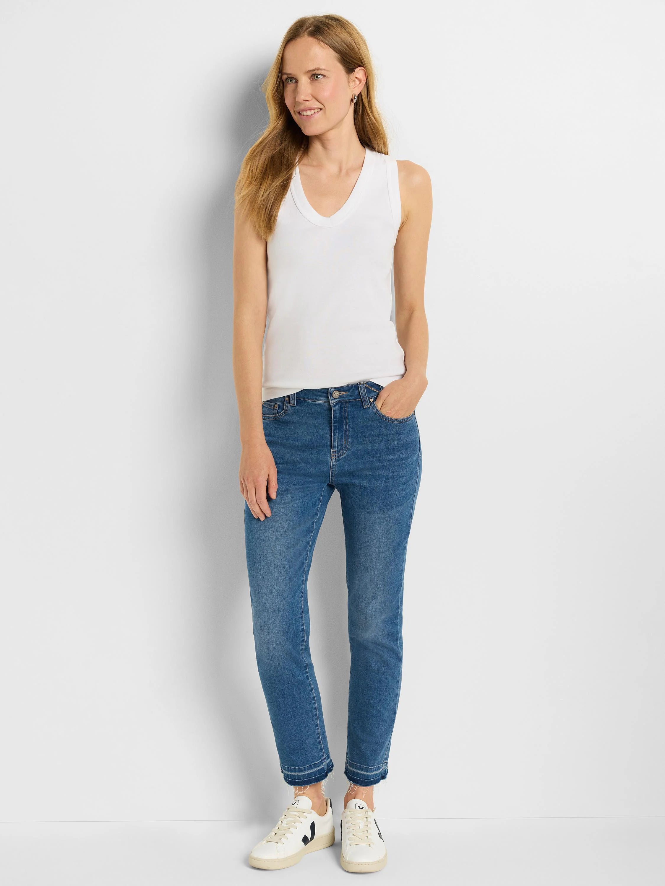 Medium blue straight jeans with a released, frayed hem, worn by a model.