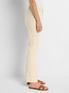 Off-white straight-leg jeans shown on a model.  The jeans have a light beige color. The model is wearing brown sandals.