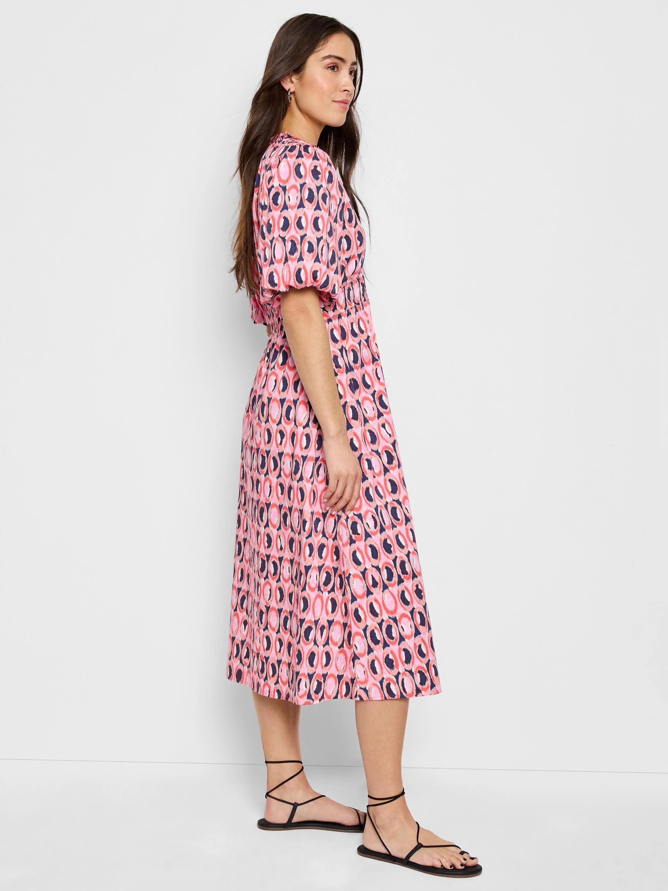Pink midi dress with a dark-blue and coral circular pattern, puff sleeves, and a fitted waist.