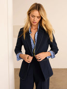 Navy blazer with light contrast stitching on lapels, front edges, and rolled cuffs.