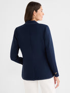 A tailored navy blazer features white contrast stitching on the hem and collar.