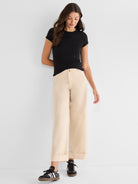 Fitted black ribbed tee and beige high-rise wide-leg trousers that are cropped and finished with thick cuffs.