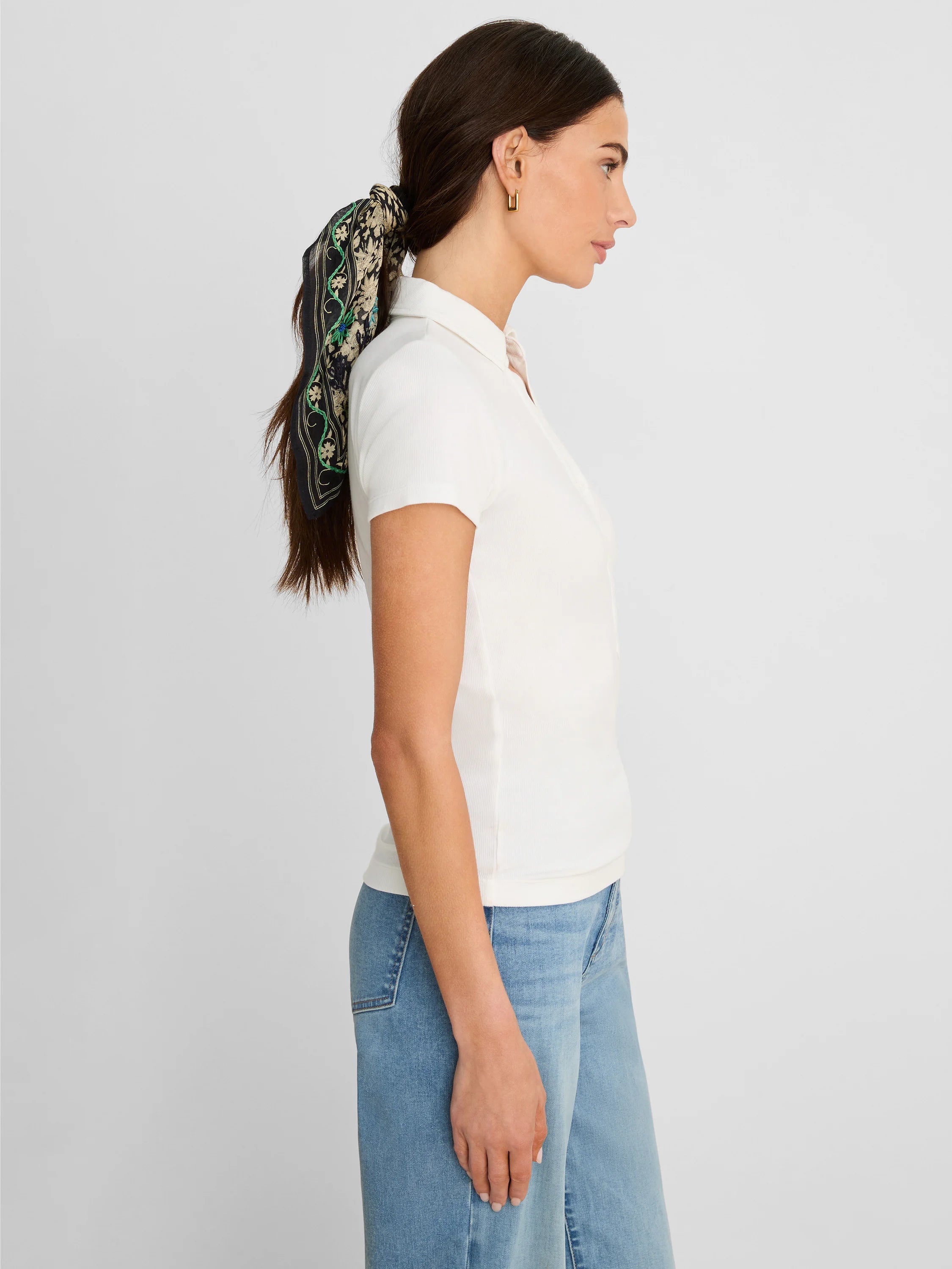 Off-white ribbed knit short sleeve polo shirt on a woman, paired with light blue jeans.