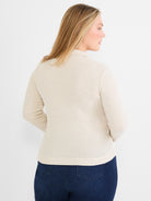 A semi-fitted light beige sweater jacket features a dense textured knit, long sleeves, and a soft collar detail.