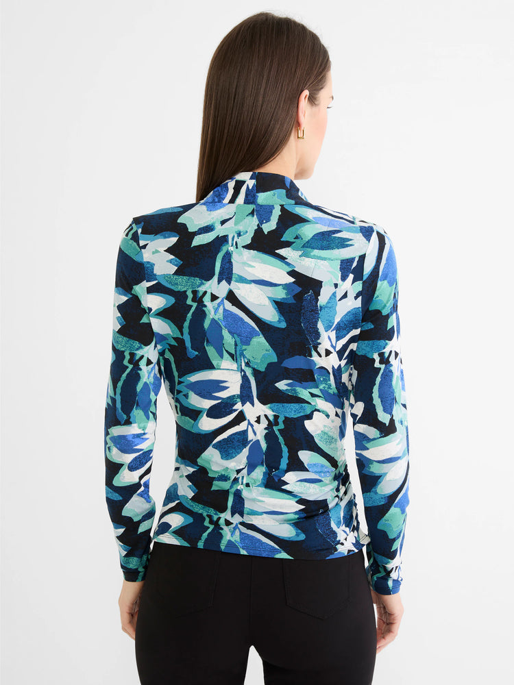 Back of a woman wearing a long-sleeve knit top with an abstract leaf pattern in shades of blue, teal, and white.