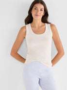 Off-white, finely ribbed scoop tank top, shown fitted on a model wearing light blue pants.