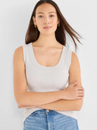 Model wearing a light grey ribbed knit scoop tank top with a wide U-neck.