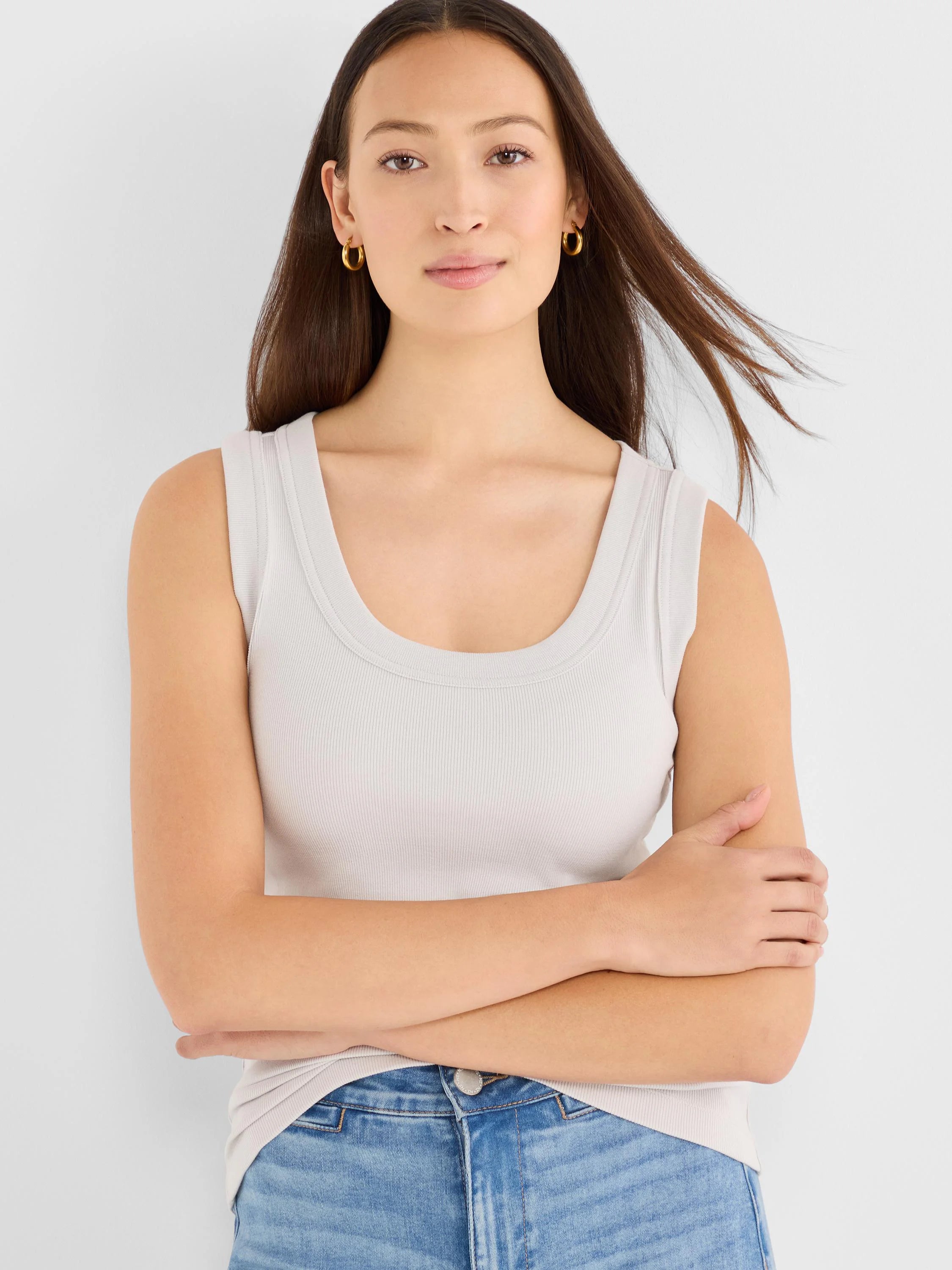 Model wearing a light grey ribbed knit scoop tank top with a wide U-neck.