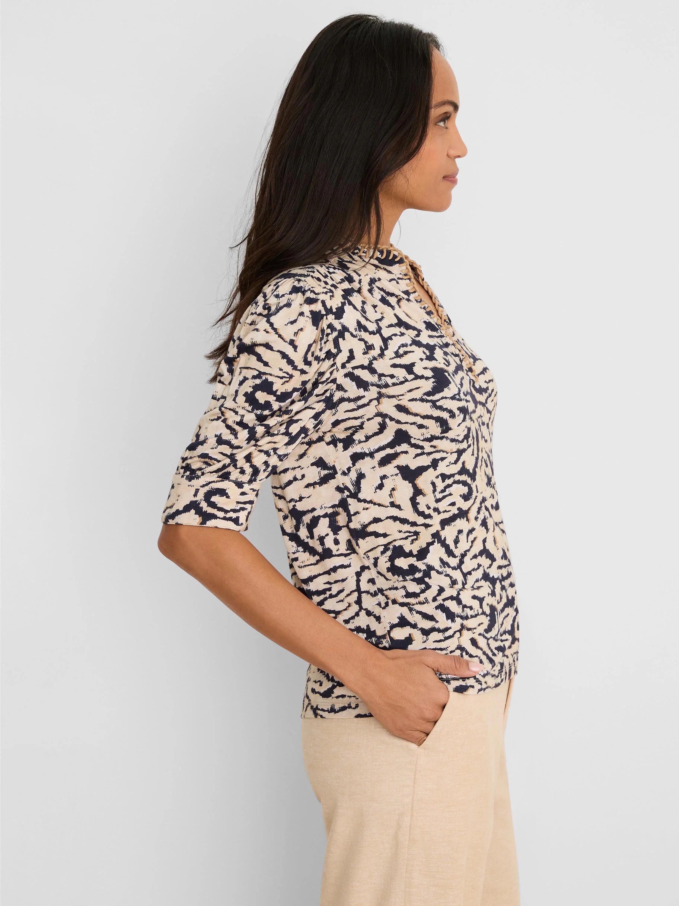 Cream top with dark blue abstract swirl pattern, high neckline, tan braided trim, and 3/4 sleeves.