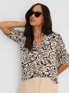 Beige top with dark blue irregular swirl pattern, braided V-neck, and three-quarter sleeves.