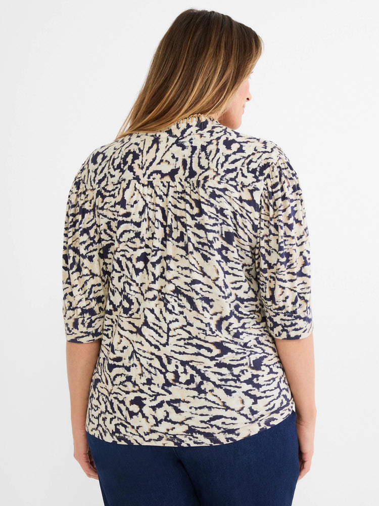 Back view of a cream top with a navy blue and brown abstract swirl pattern and 3/4 length sleeves.
