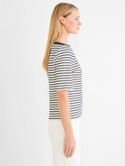 Off-white embroidered boatneck top with navy horizontal stripes, short sleeves, on model.