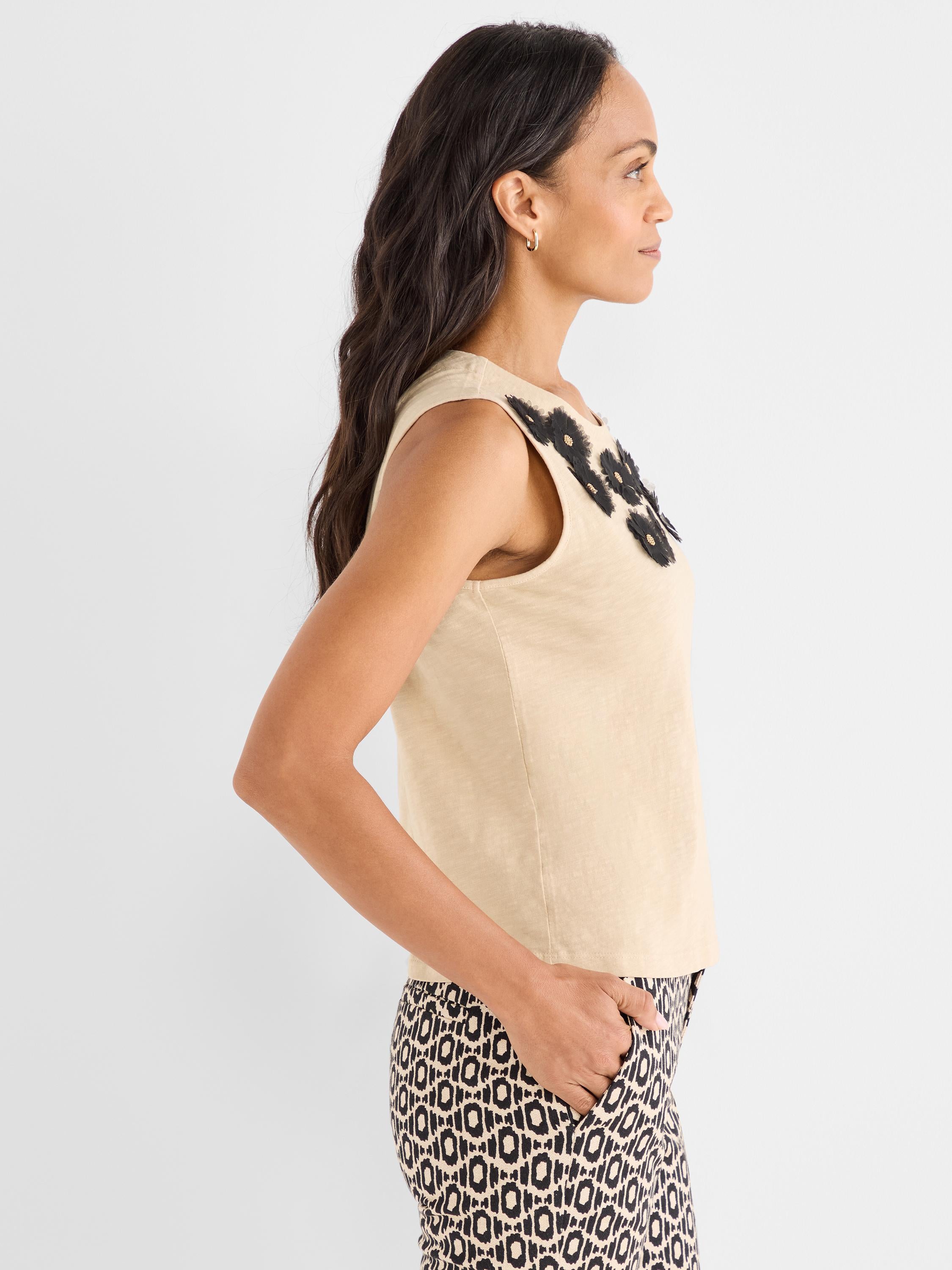 This regular fit beige sleeveless top features black textured floral appliqué detail at the neckline.
