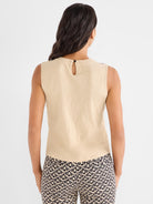 The beige sleeveless top has a relaxed fit and features a back keyhole closure with a single button detail.
