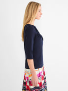 Navy blue 3/4 sleeve top with ruffled mesh applique detail on the right shoulder and chest.