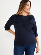 Dark navy boat neck top with 3/4 sleeves and self-color ruffled mesh appliqué across the chest.