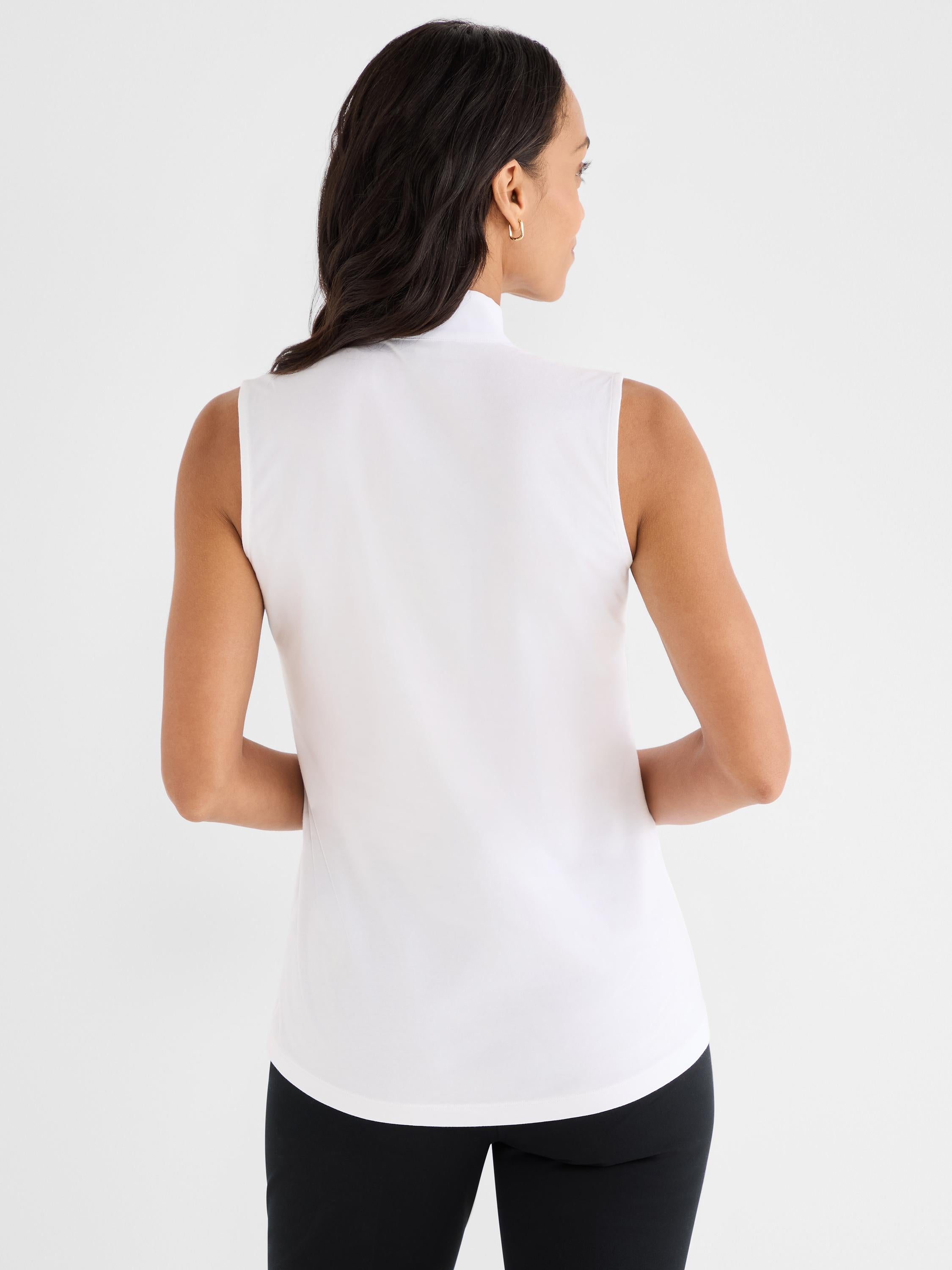 The model wears a slim-fit white sleeveless shell featuring a high mock neck collar.