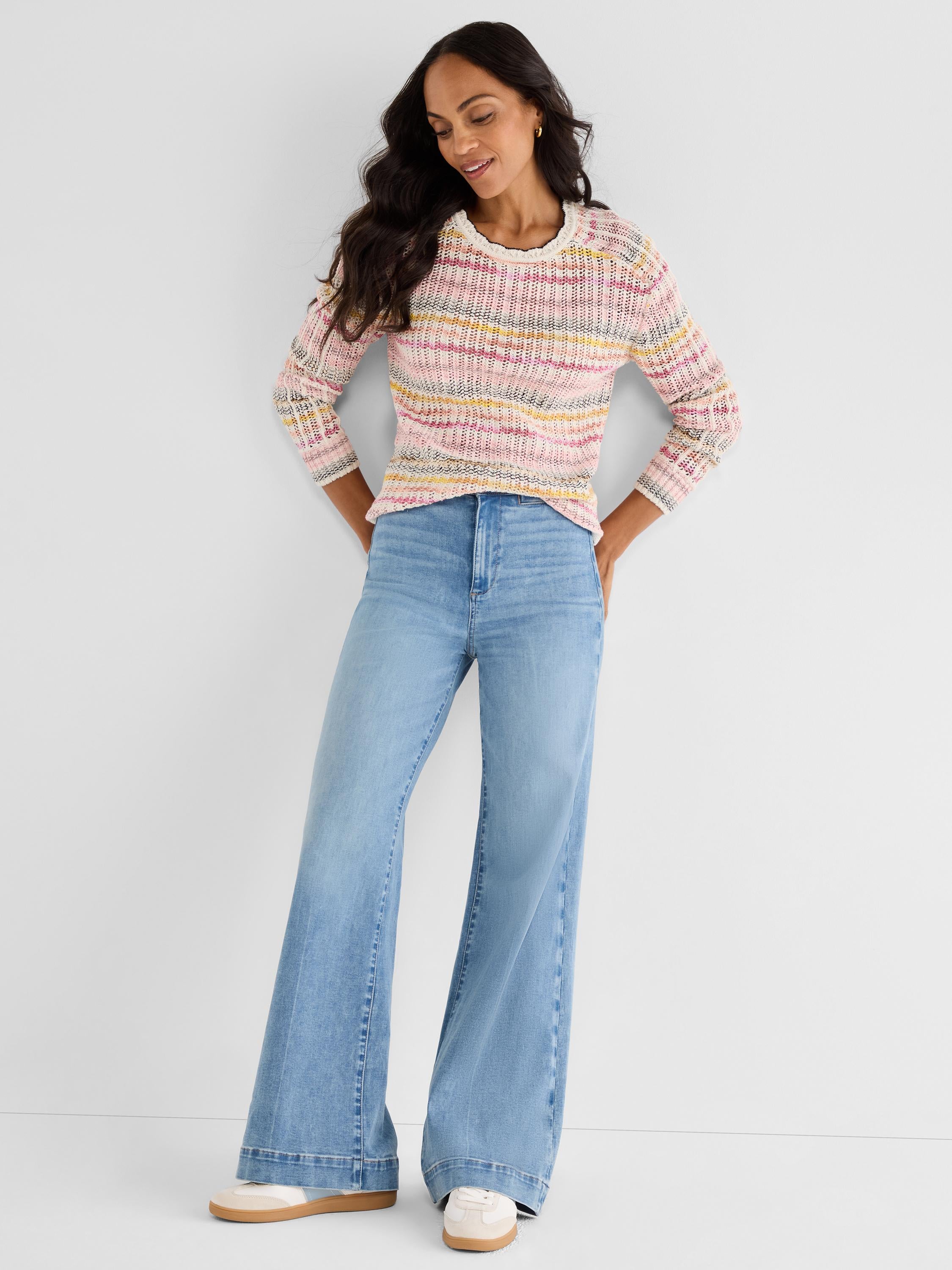 Fitted open-knit sweater featuring multicolored stripes and a fringe neck is paired with high-rise wide-leg light wash jeans.