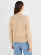 A tan relaxed-fit knit sweater features a mock neck and a prominent ribbed bottom hem.