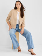 Fitted tan knit jacket with a crewneck, ribbed hem, and chunky contrasting gold button hardware.