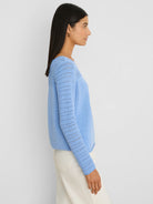 Light blue sweater with solid body and pointelle knit on sleeves.