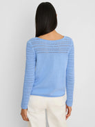 Light blue sweater shown from back. Features placed pointelle knit on shoulders & sleeves, solid knit body.