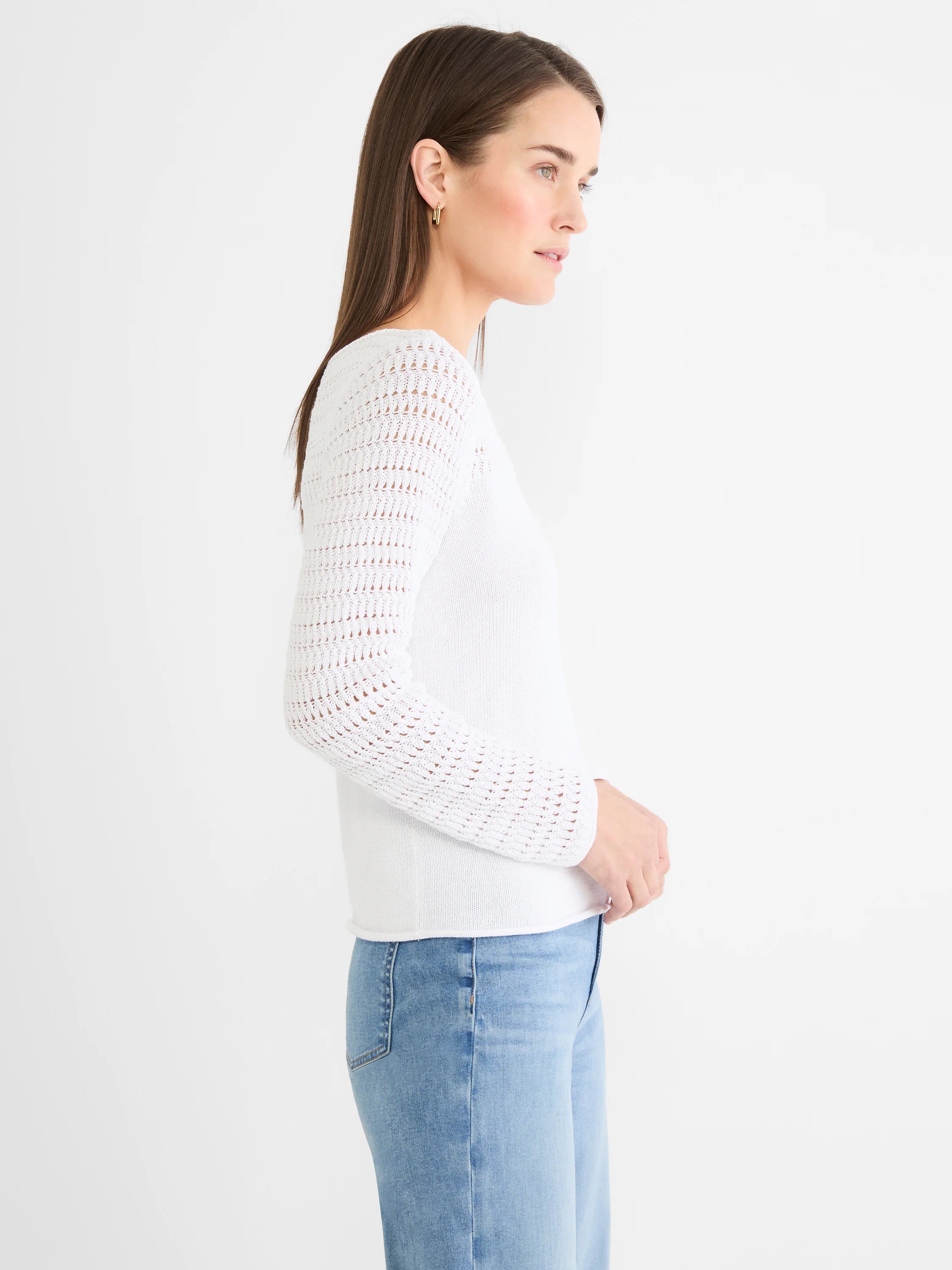 White sweater with pointelle knit sleeves and a solid knit body. Worn with light wash jeans.