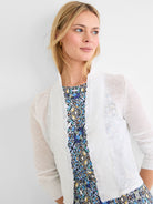 White sheer cardigan with ruffles along the front opening and ribbed cuffs.